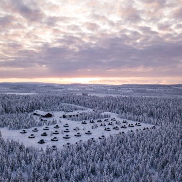 Aerial view of snow-covered Arctic forest and wilderness lodges at dusk